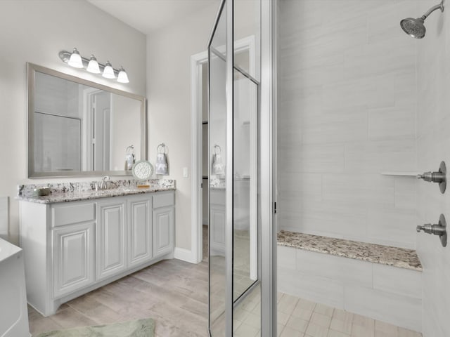 bathroom with a tile shower, vanity, and wood-type flooring