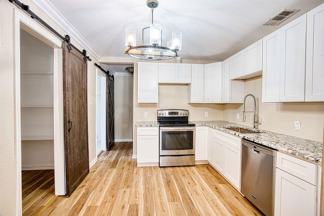 kitchen featuring white cabinetry, stainless steel appliances, an inviting chandelier, sink, and a barn door