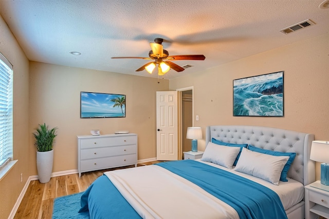 bedroom featuring a textured ceiling, ceiling fan, and light hardwood / wood-style flooring