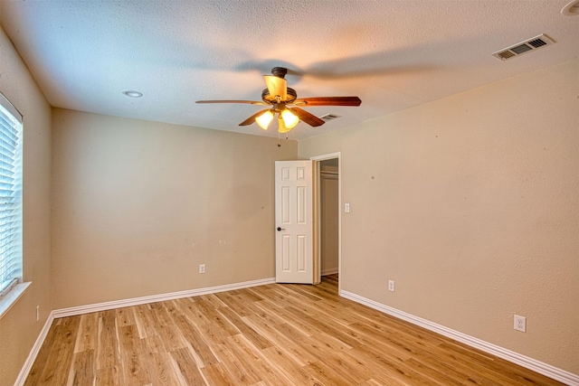 empty room featuring ceiling fan, a textured ceiling, and light hardwood / wood-style flooring