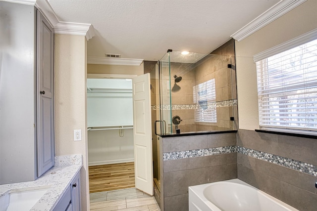 bathroom with plus walk in shower, ornamental molding, a textured ceiling, and vanity