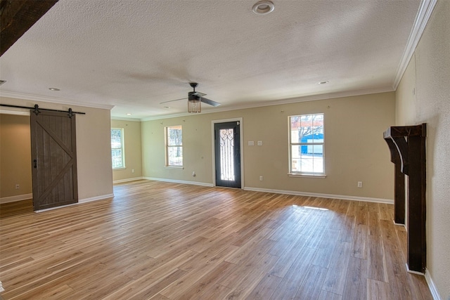 unfurnished living room featuring crown molding, a barn door, and light hardwood / wood-style floors