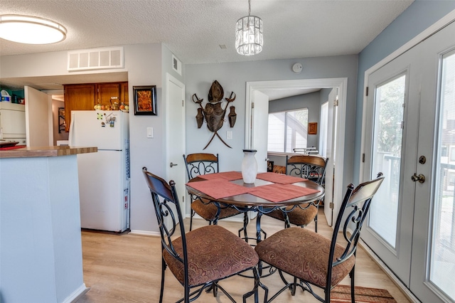 dining room with a notable chandelier, a textured ceiling, and light hardwood / wood-style floors