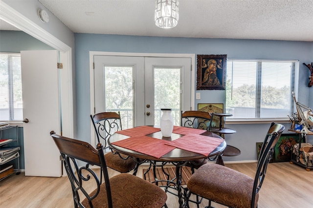 dining space featuring french doors, a textured ceiling, and light hardwood / wood-style flooring