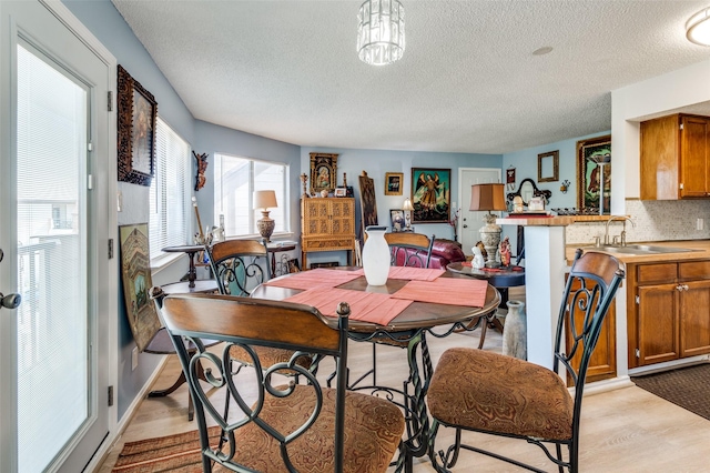 dining space with sink, a textured ceiling, and light hardwood / wood-style floors