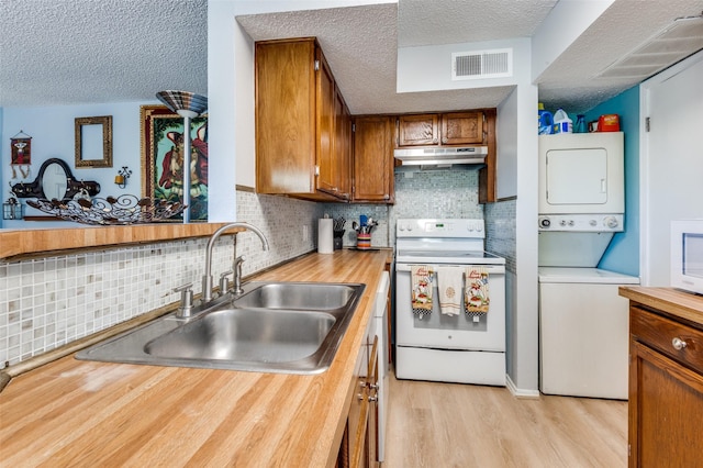 kitchen with sink, light hardwood / wood-style flooring, a textured ceiling, white electric stove, and stacked washing maching and dryer