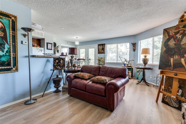 living room featuring french doors, light hardwood / wood-style floors, and a wealth of natural light