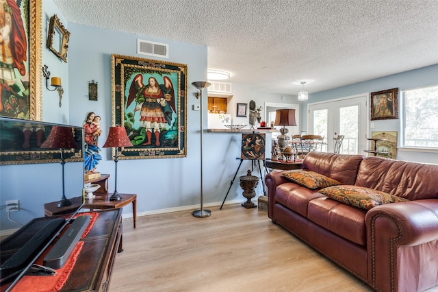 living room featuring light hardwood / wood-style flooring, french doors, and a textured ceiling