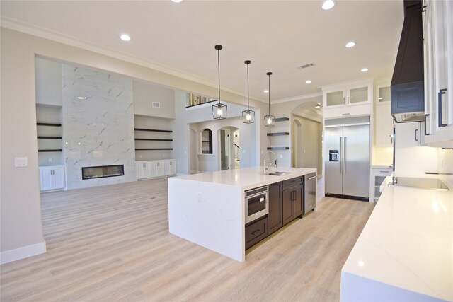 kitchen featuring pendant lighting, sink, an island with sink, custom range hood, and stainless steel appliances