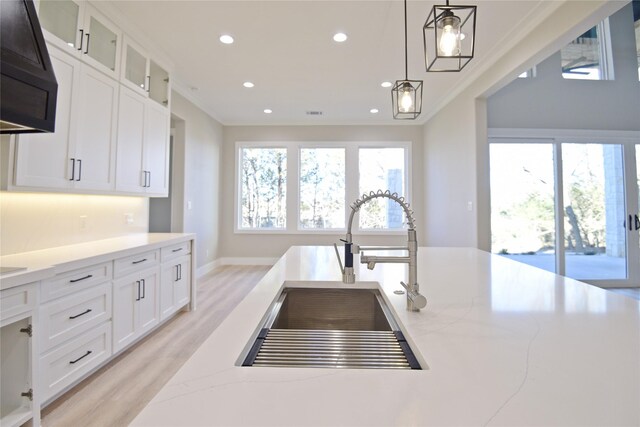 kitchen featuring white cabinetry, a high end fireplace, light hardwood / wood-style floors, a center island with sink, and appliances with stainless steel finishes