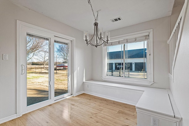 unfurnished dining area with a notable chandelier and light wood-type flooring