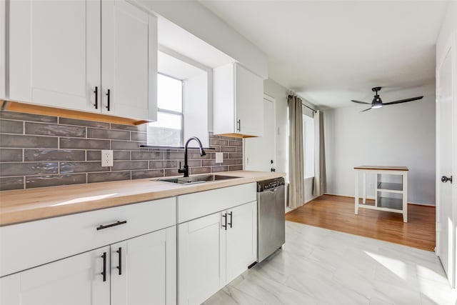 kitchen featuring stainless steel dishwasher, white cabinetry, tasteful backsplash, and sink