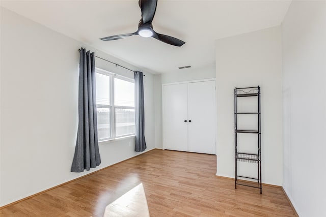 unfurnished bedroom featuring light wood-type flooring, ceiling fan, and a closet