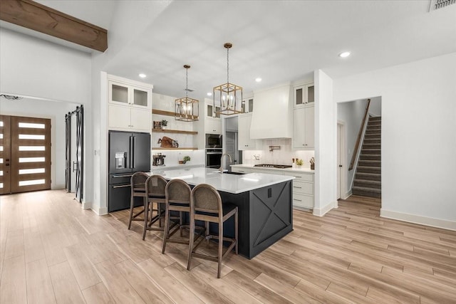 kitchen featuring white cabinets, appliances with stainless steel finishes, a center island with sink, and sink