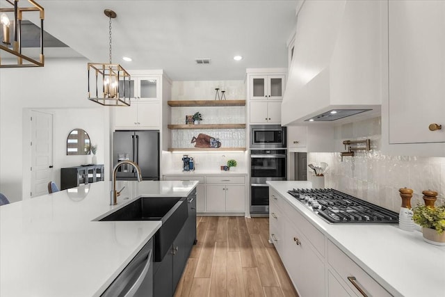 kitchen with white cabinets, backsplash, pendant lighting, and stainless steel appliances