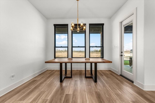 unfurnished dining area with hardwood / wood-style floors and an inviting chandelier