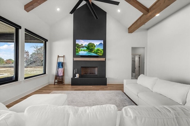 living room with a tile fireplace, ceiling fan, lofted ceiling with beams, and light hardwood / wood-style floors