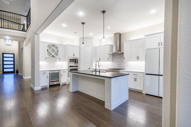 kitchen with built in appliances, white cabinets, beverage cooler, and wall chimney range hood