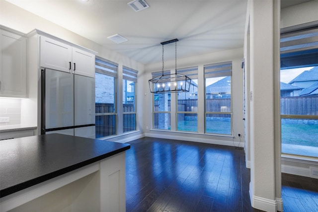 kitchen featuring dark wood-type flooring, white cabinetry, an inviting chandelier, decorative light fixtures, and stainless steel fridge