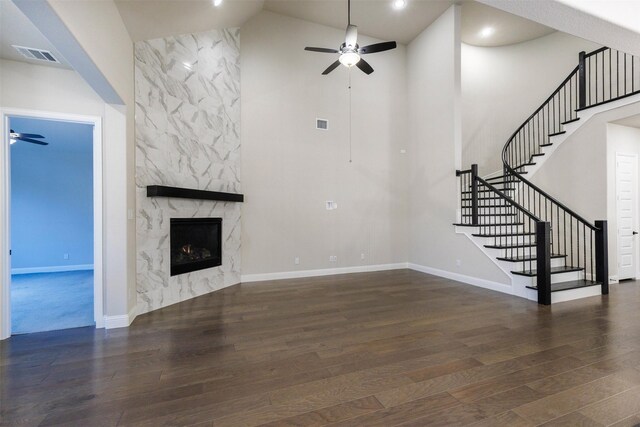 unfurnished living room with ceiling fan, a high end fireplace, dark hardwood / wood-style floors, and high vaulted ceiling