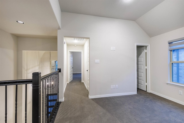 corridor with lofted ceiling and dark colored carpet