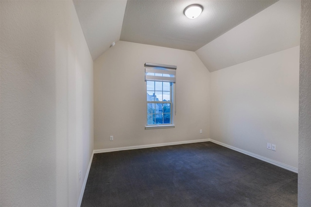 additional living space featuring dark colored carpet and lofted ceiling