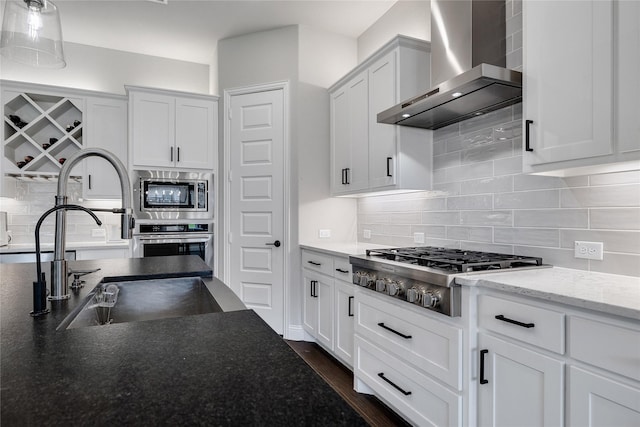 kitchen featuring decorative backsplash, wall chimney exhaust hood, stainless steel appliances, sink, and white cabinets