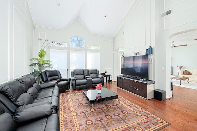 living room with ornamental molding, high vaulted ceiling, ceiling fan, and light wood-type flooring