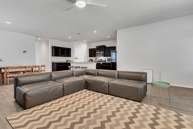 living room featuring light hardwood / wood-style flooring, ceiling fan, and sink