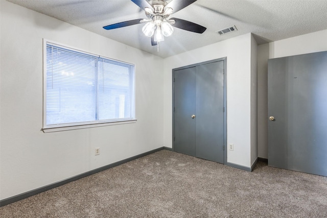 unfurnished bedroom featuring light carpet, a textured ceiling, a closet, and ceiling fan