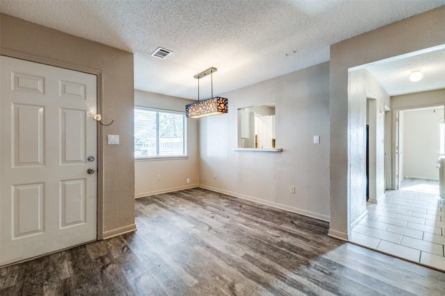 unfurnished dining area with dark hardwood / wood-style flooring and a textured ceiling