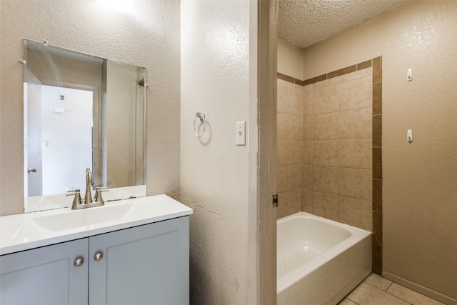 bathroom with tile patterned floors, vanity, a textured ceiling, and tiled shower / bath