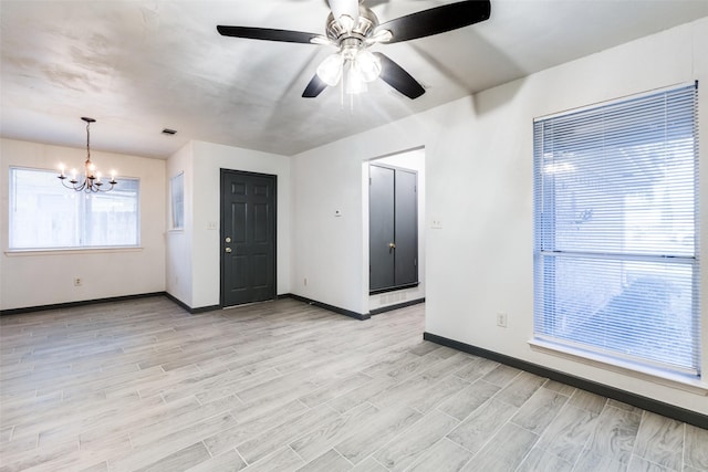 unfurnished room with ceiling fan with notable chandelier and light wood-type flooring