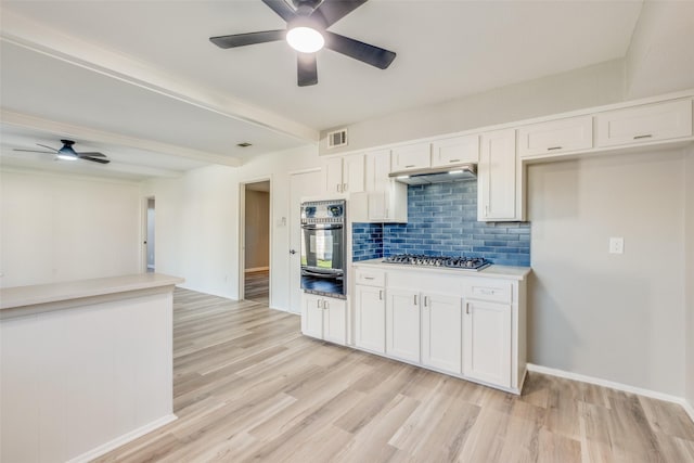 kitchen featuring white cabinetry, tasteful backsplash, light hardwood / wood-style floors, stainless steel gas stovetop, and black oven