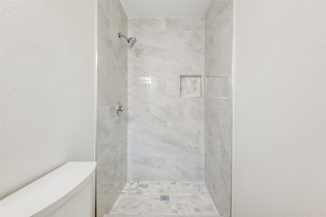 bathroom featuring tiled shower and toilet