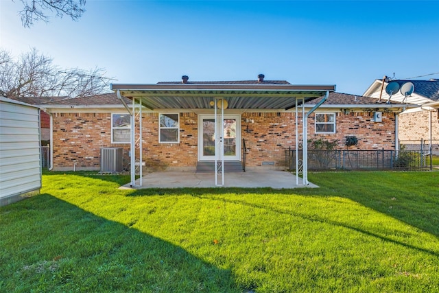 rear view of property with central air condition unit, a lawn, and a patio