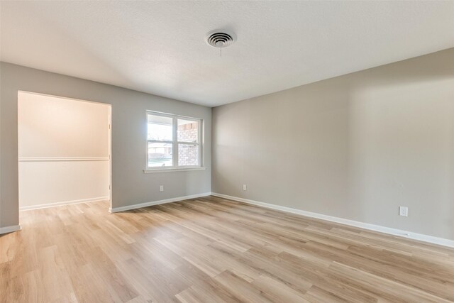 empty room with a textured ceiling and light wood-type flooring