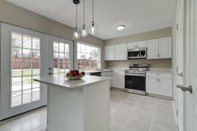 kitchen with stainless steel appliances, sink, white cabinetry, light tile patterned flooring, and hanging light fixtures