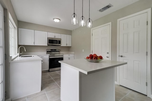 kitchen with decorative light fixtures, white cabinets, appliances with stainless steel finishes, light tile patterned flooring, and sink