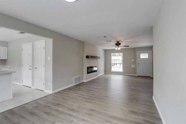 unfurnished living room featuring ceiling fan and light hardwood / wood-style flooring