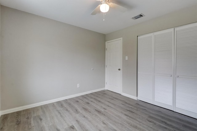 unfurnished bedroom featuring ceiling fan, light hardwood / wood-style floors, and a closet