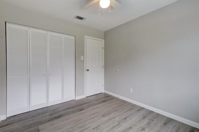 unfurnished bedroom featuring ceiling fan, light wood-type flooring, and a closet