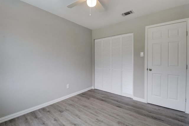 unfurnished bedroom with wood-type flooring, a closet, and ceiling fan