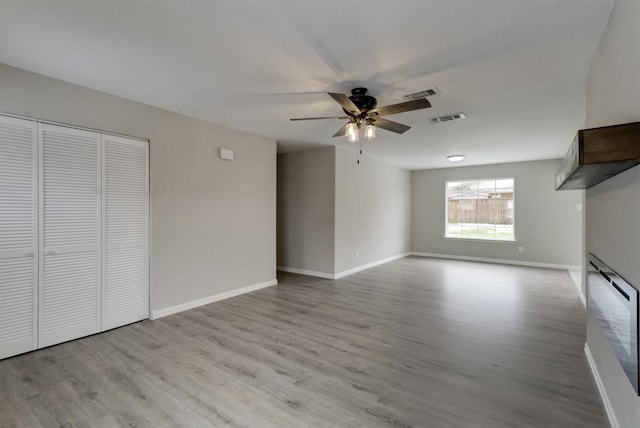 unfurnished living room featuring ceiling fan and light wood-type flooring