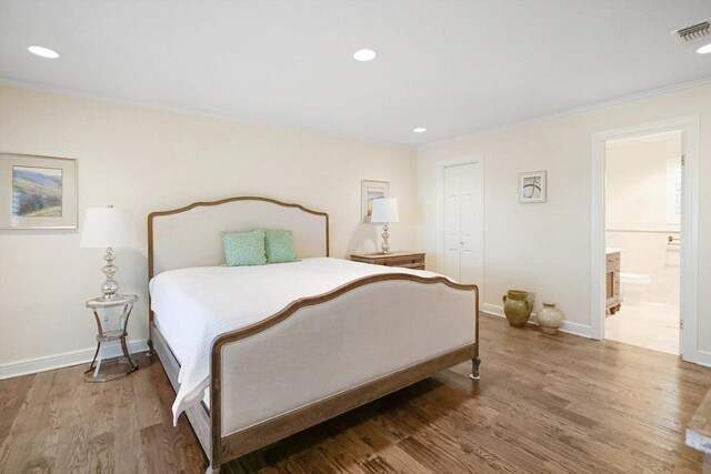 bedroom with crown molding, ensuite bath, and hardwood / wood-style floors