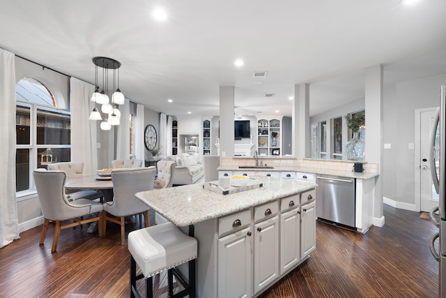 kitchen with white cabinets, stainless steel dishwasher, dark hardwood / wood-style floors, and a kitchen island