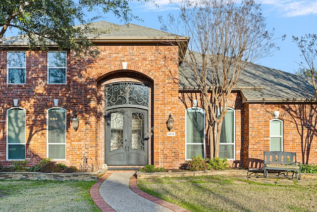 view of exterior entry with a yard and french doors