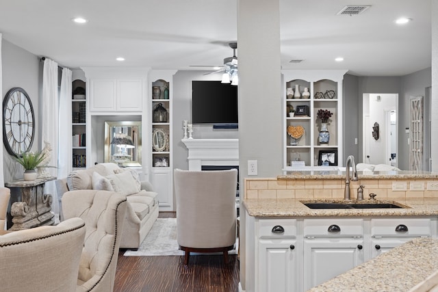 living room featuring ceiling fan, sink, and dark hardwood / wood-style floors