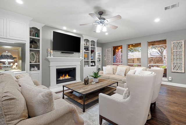 living room featuring ceiling fan, built in shelves, and wood-type flooring