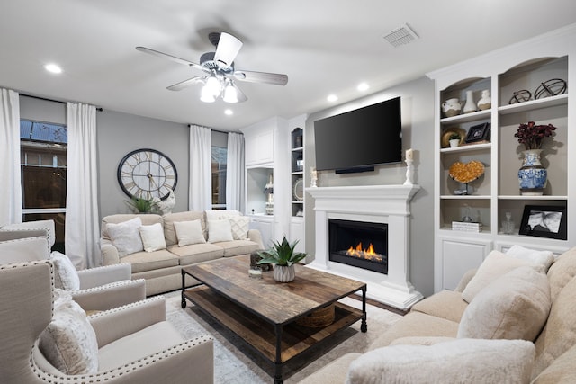 living room with built in shelves and ceiling fan